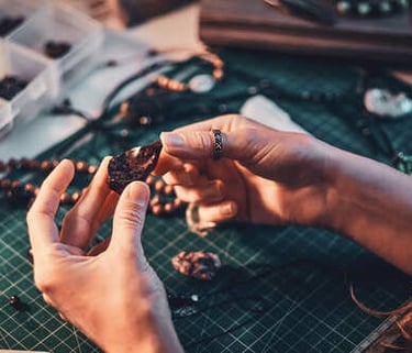 Joyero artesano inspeccionando una piedra preciosa naturales en bruto en un banco de trabajo