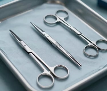 A macro photograph of several neurosurgical micro-scissors laid out in a row on a sterile light grey-blue surgical tray. The lighting is clean and professional, focusing on the sharp edges and sleek design.