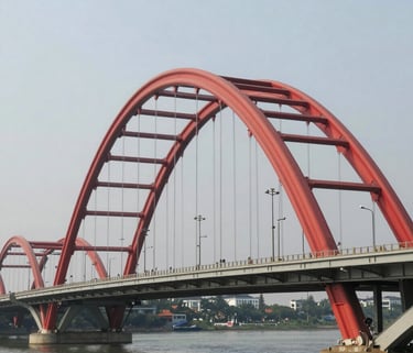 Close-up of a professional spray gun applying red paint on a metal surface.