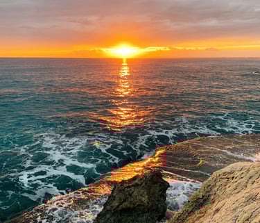 Golden Cyprus sunset with waves crashing against a rocky Mediterranean coastline.