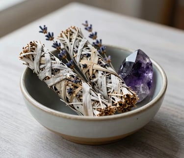 Photography of a ceramic bowl containing white sage bundles, dried lavender, and a polished amethyst crystal on a light grey wooden table, North American / US sanctuary setting, soft natural morning light, serene atmosphere.