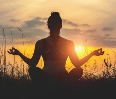femme de dos en position de méditation en exterieur