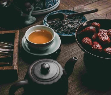 Rustic tea scene with teacup, black teapot, dried dates and loose leaves