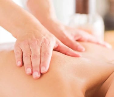Close up of a massage therapist's hands applying pressure to a patient's back. 