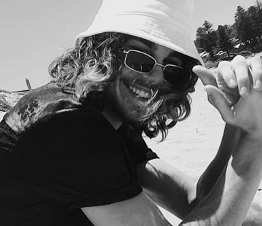 a man in a hat and sunglasses on a beach