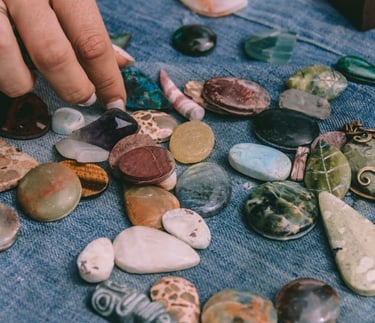 Una mano seleccionando piedras preciosas pulidas y cristales curativos exhibidos sobre una tela azul