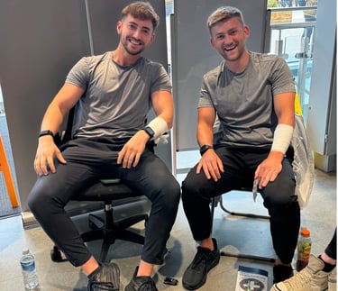 2 first aid trainers demonstrating practical bandage skills while seated with training equipment 