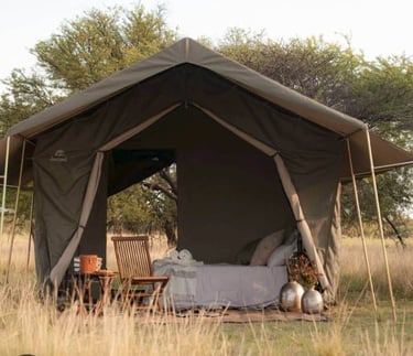 Luxury safari glamping tent with comfortable bedding and wooden furniture in the African Karoo.