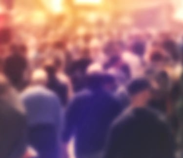 An very diffuse image with a crowd of people walking on a city street.