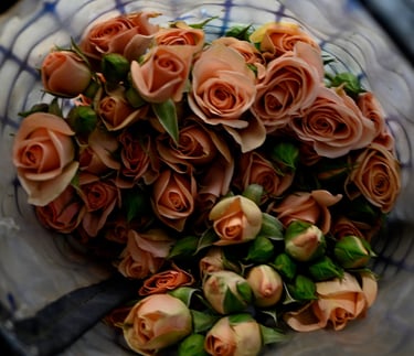 A fresh bouquet of peach-colored spray roses and green flower buds in a floral mesh wrap.