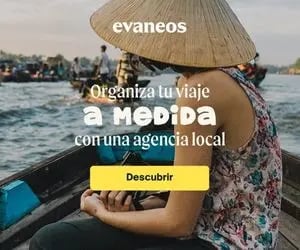 A woman in a traditional conical hat travels by boat on a river in Vietnam with a local travel agency.