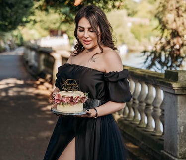 Model holding birthday cake in elegant black dress, captured by Fred Art Studio.