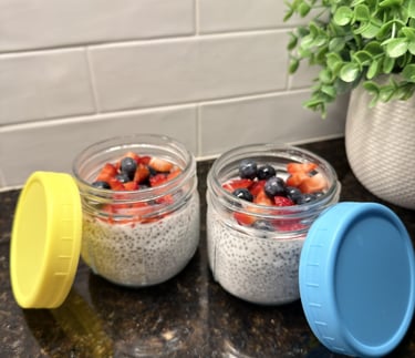 Two glass jars of chia seed pudding topped with berries on a kitchen counter for weekly meal prep