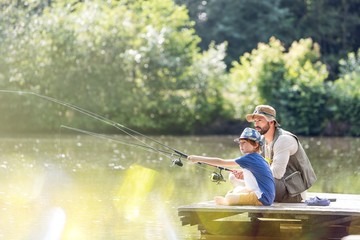 pai e filho pescando em um porto no lago com arvores ao fundo