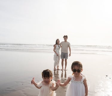 Family walking  along the shoreline at Petitenget Beach Seminyak Bali during a relaxed lifestyle family photography session