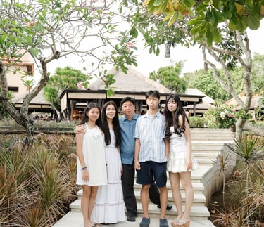 Family gathered in a tropical garden setting during a natural lifestyle session at Ayana Resort Jimbaran Bali