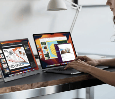 a female student sitting at a desk with a laptop and a portable monitor