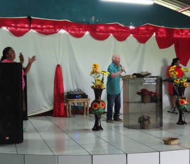 Pastor Esmerito Reyes stands behind a podium preaching to a congregation.