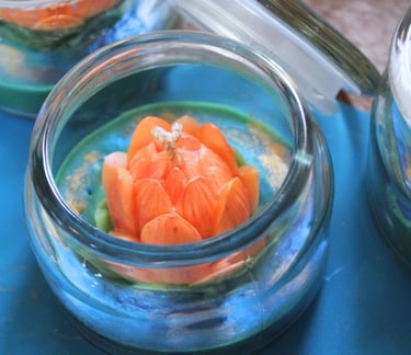 A close-up of a decorative lotus-shaped candle inside a glass jar.