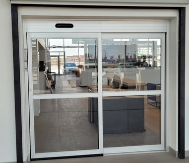 Automatic sliding glass doors with a white frame at a modern commercial building entrance.