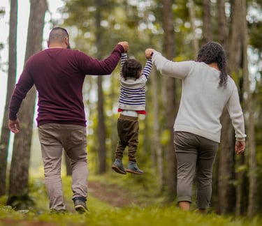 Couple walking through the wood with a young child in between them