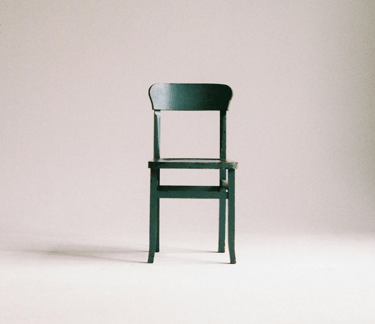 Een lege houten stoel staat uitnodigend klaar, symbool voor de ouder die nog niet in gesprek is.