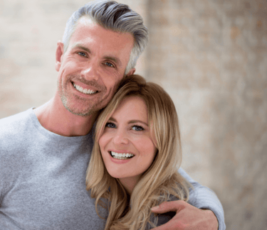 a man and woman smiling and hugging each other