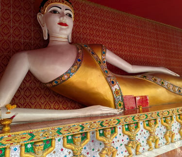 Reclining golden Buddha statue with red and gold wall in a Buddhist temple, Thailand.