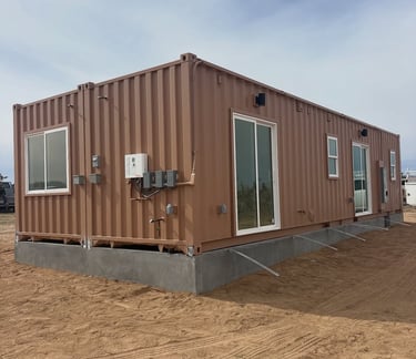 Modern brown shipping container home on a concrete foundation with sliding glass doors and windows.