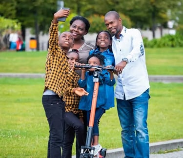 large young African American family smiling at the park with a scooter, taking a selfie