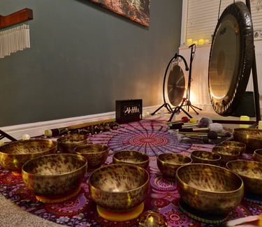 Shruti box, chimes, gongs, and many singing bowls arranged on a mat