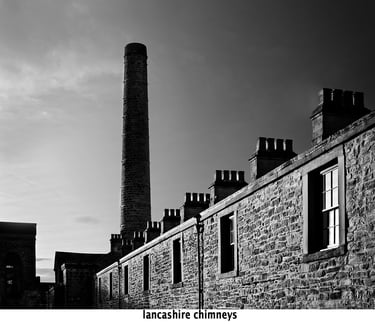 a mill chimney and adjacent mill cottages with chimneys