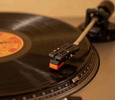 Macro shot of a vintage turntable needle resting on a vinyl record, warm amber studio lighting, rich dark tones, 35mm