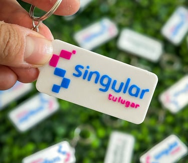 Hand holding a white rectangular custom 3D printed  3d llaveros posadas with the Singular logo.