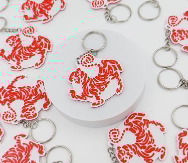Red and white acrylic tiger dojo 3d llaveros posadas  with silver metal rings on a white background.