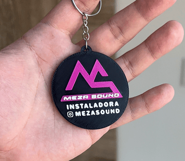 Custom 3D printed Meza Sound logo keychain in black and pink held in a hand.