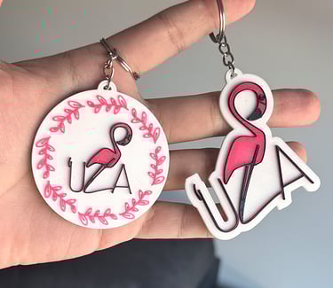 Custom 3D printed flamingo keychains featuring pink bird designs and personalized UZA text.