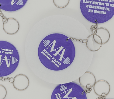 Custom purple 3D printed keychains for personal trainer Magali Aquino featuring a barbell logo.