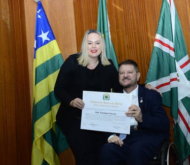 um homem em uma cadeira de rodas entregando um certificado para uma mulher