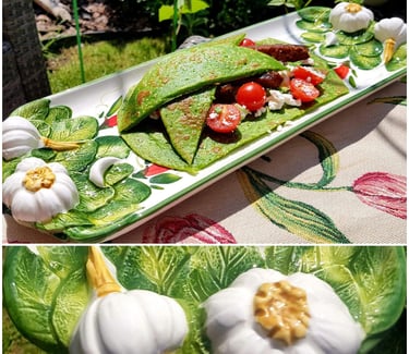 Savory green spinach crepes filled with steak, cherry tomatoes, and feta on a garlic-themed ceramic platter.