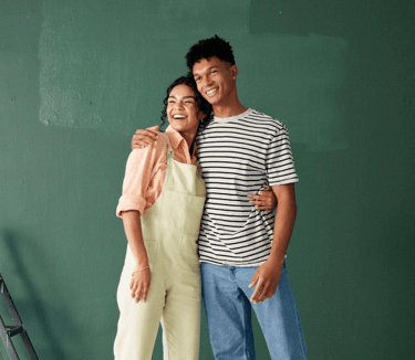 a man and woman standing in front of a green wall