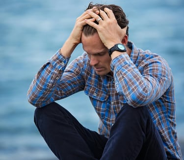 Photo d'un homme se prenant la tête entre les mains représentant le deuil et la détresse psychologique