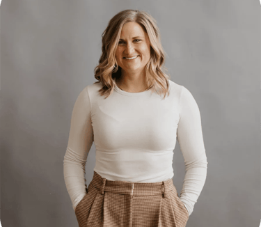 A professional portrait of a woman named Callan Faulkner, smiling while wearing a white long-sleeved