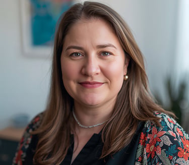 Professional headshot of a smiling woman with brown hair wearing a floral patterned cardigan.