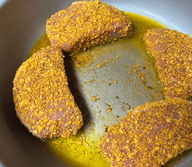 Battered pork chops starting their sear in pan