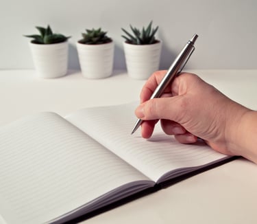 una mano che impugna una penna per scrivere su un diario