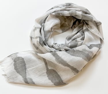 Lightweight white scarf with gray abstract patterns, arranged in a loose spiral on a white background