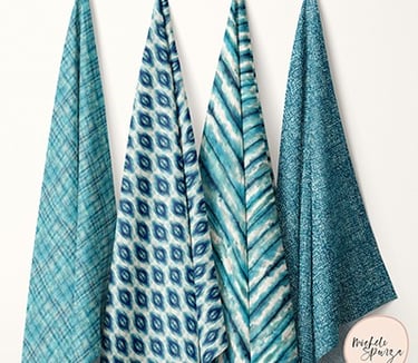 4 teal blue textile samples with patterns, including plaid, ikat, shibori, and watercolor texture, displayed side by side