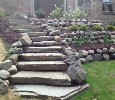 Leppek Landscape designed and installed steps, retaining wall, boulders, shrubs and trees. 
