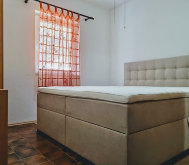 The photo shows a double bed and a window with a curtain in the apartment's bedroom.